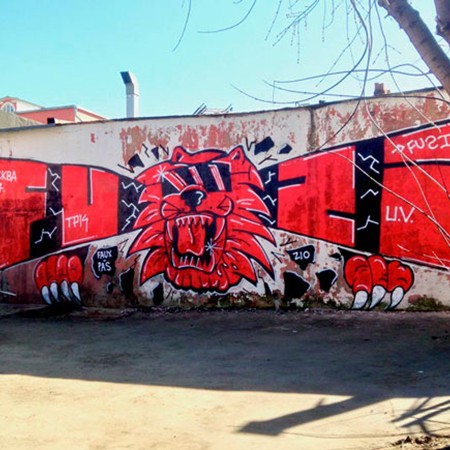 Lettrages et personnage rouge sur mur par le graffeur Fuzi