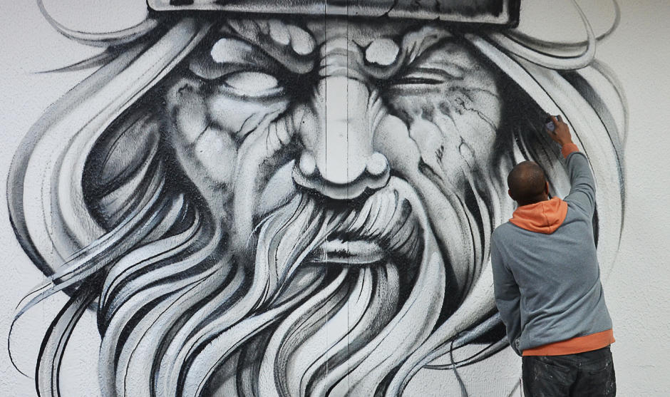 graffeur peignant un visage d'un homme barbu sur un mur